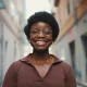 Cheerful African woman in glasses looking happy outdoors. Carefree dark-skinned girl sincerely smiling on the street. Girl looking at camera